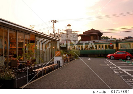 赤いクルマの脇を江ノ電が走る風景 31717394