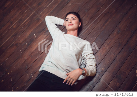 Attractive brunette in a gray sweatshirt lies on a Attractive brunette in a gray sweatshirt lies on a 31717612