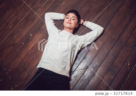 Attractive brunette in a gray sweatshirt lies on a Attractive brunette in a gray sweatshirt lies on a 31717614