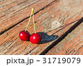 Two cherries are on a wooden table 31719079