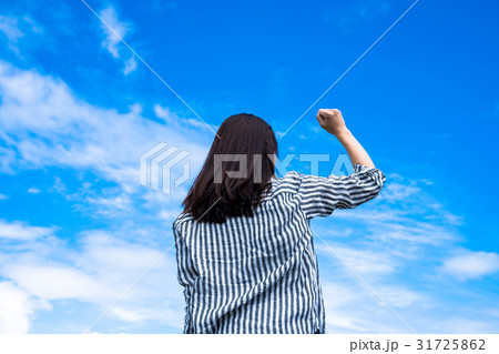 青空にガッツポーズする女性の写真素材