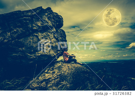 Woman sitting on boulders, sky and full moon. 31726382