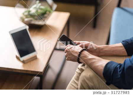 Youthful guy using mobile phone inside sitting Youthful guy using mobile phone inside sitting 31727985