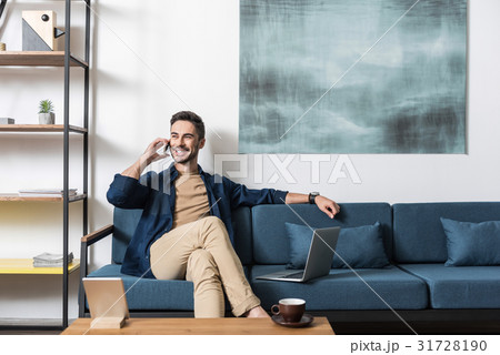 Cheery attractive guy working from home via modern 31728190