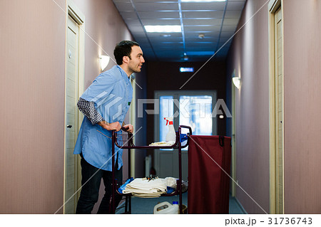 Young man pushing a housekeeping cart laden with 31736743
