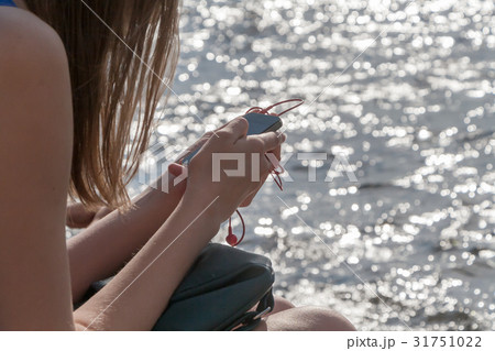 the girl with phone sits at water 31751022