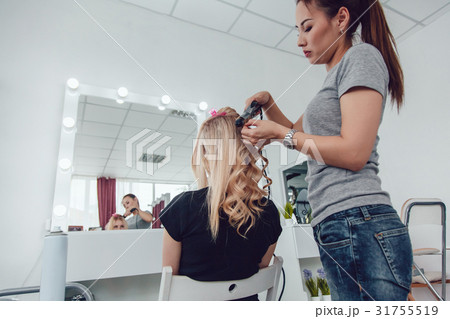 Hair stylist makes a curls for a girl, using hair Hair stylist makes a curls for a girl, using hair 31755519