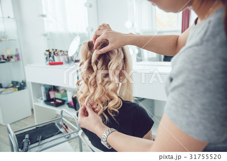 Hair stylist makes a curls for a girl, using hair Hair stylist makes a curls for a girl, using hair 31755520