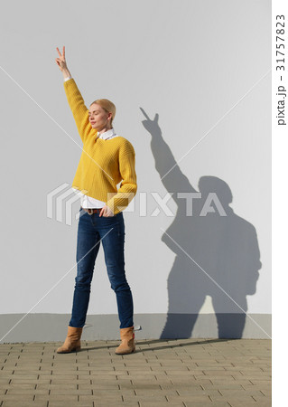 Girl posing in front of the wall with funny shadow Girl posing in front of the wall with funny shadow 31757823