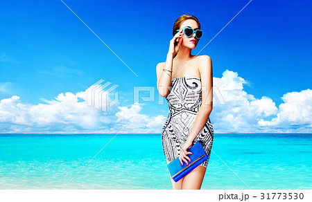 ビーチ沿いのサングラスをかけた外国人女性の写真素材