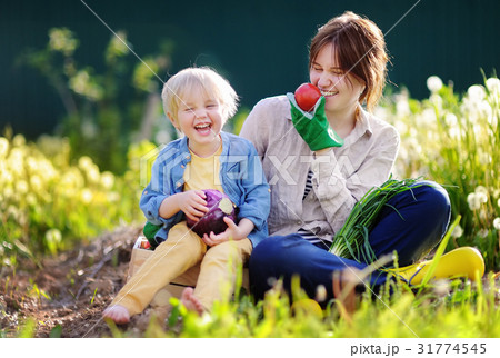 Young woman and her adorable little son enjoying harvest Young woman and her adorable little son enjoying harvest 31774545