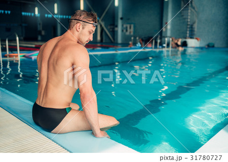 Athletic male swimmer sits on the curb, back view Athletic male swimmer sits on the curb, back view 31780727