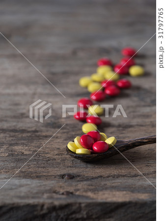 Red yellow pills and wood spoon on wood 31797765