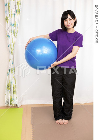 バランスボールを持って立つ女性の写真素材