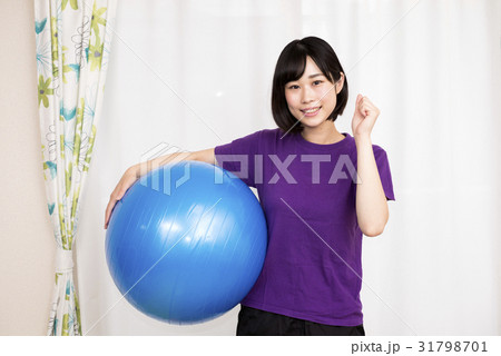 バランスボールを抱えてガッツポーズする女性の写真素材