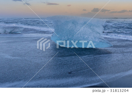 Ice breaking on black sand beach with sunset sky  31813204