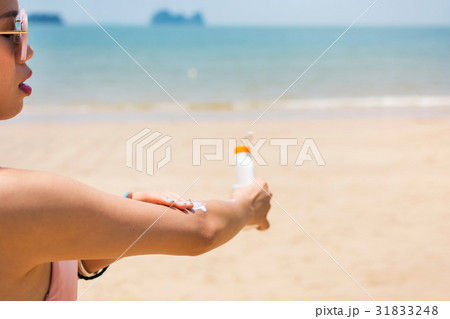 Girl applying sun lotion on the beach 31833248