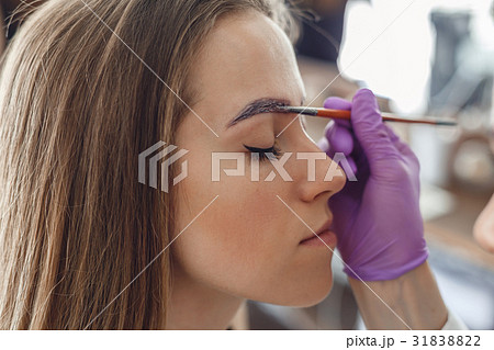 Master painting client eyebrows in the salon. Master painting client eyebrows in the salon. 31838822