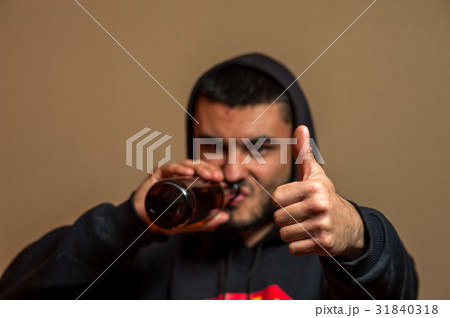 Young man drinking beer and showing thumbs up Young man drinking beer and showing thumbs up 31840318