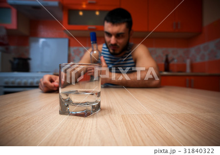 Young depressed man taking alcohol in kitchen Young depressed man taking alcohol in kitchen 31840322