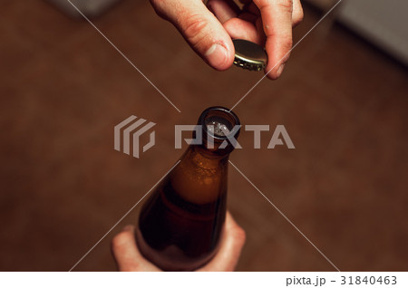 Closeup of male hands opening beer bottle. 31840463