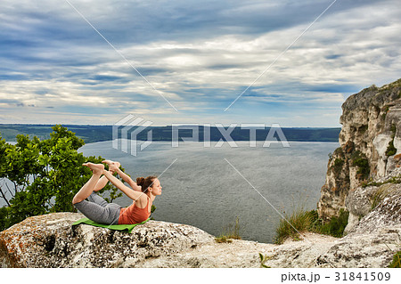 Young sportive woman training yoga on rock against Young sportive woman training yoga on rock against 31841509