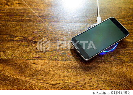 Smartphone charging on a charging pad. Wireless Smartphone charging on a charging pad. Wireless 31845499