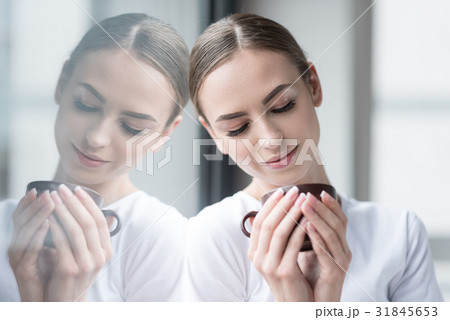 Jolly young beautiful woman drinking hot beverage 31845653