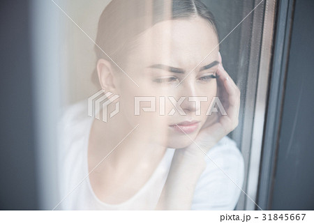 Sad youthful woman watching bad weather at home Sad youthful woman watching bad weather at home 31845667