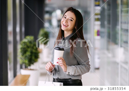 Brunette girl drinks a coffee from a large paper Brunette girl drinks a coffee from a large paper 31855354