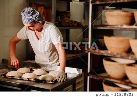 a Baker makes manual incisions on the dough for 31859803