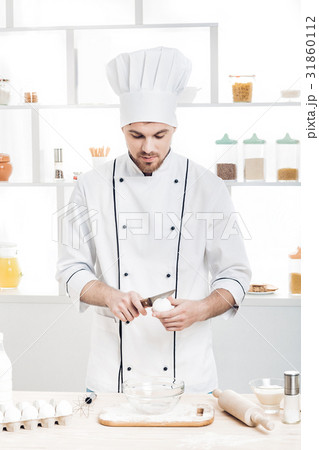 Chef in uniform breakseggs in bowl to prepare Chef in uniform breakseggs in bowl to prepare 31860112