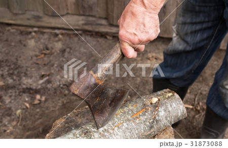 an elderly man with an old axe chops firewood 31873088