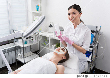 Joyful cosmetologist is working with client at spa 31873644