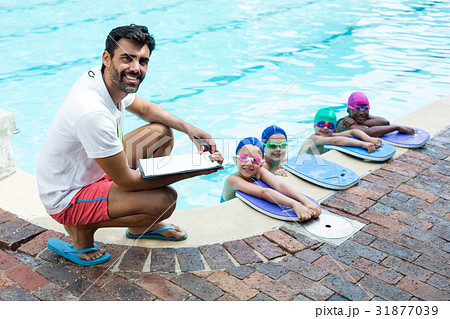 Male instructor with little swimmers at poolside 31877039