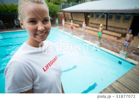 Confident instructor standing at poolside Confident instructor standing at poolside 31877072