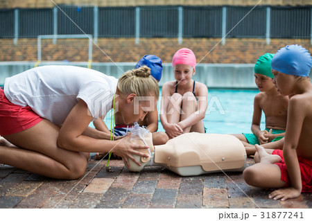 Female lifeguard demonstrating children during rescue training Female lifeguard demonstrating children during rescue training 31877241