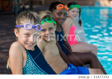 Row of friends sitting at pool side 31877242
