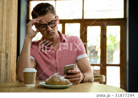 Tensed man using smart phone in coffee shop 31877294