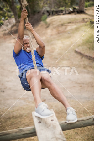 Fit man climbing a rope during obstacle course Fit man climbing a rope during obstacle course 31877321