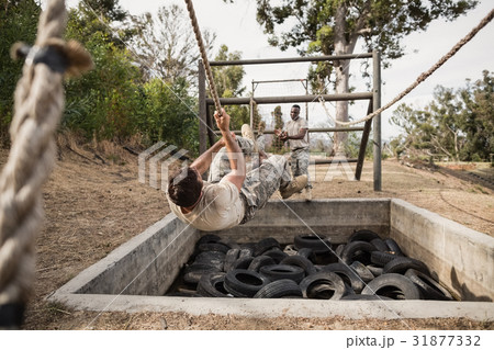 Young military soldiers practicing rope climbing during obstacle course 31877332