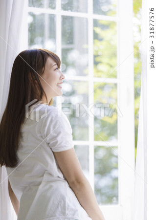 窓辺に佇む女性の写真素材