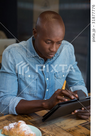 Man using digital tablet at wooden table in coffee house Man using digital tablet at wooden table in coffee house 31877776