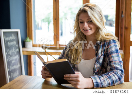 Smiling woman reading book at table in coffee shop 31878102