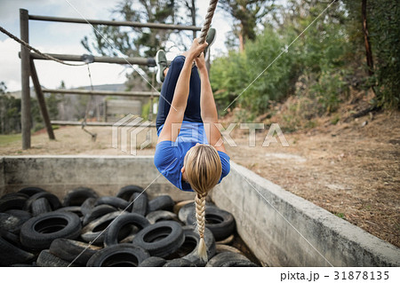Woman climbing rope during obstacle course training Woman climbing rope during obstacle course training 31878135