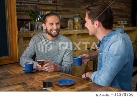 Smiling man talking with friend at table in coffee shop 31878256