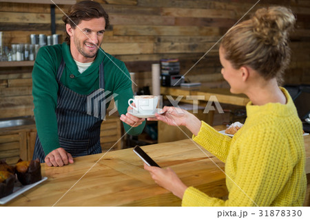 Barista serving coffee to female customer in cafeteria Barista serving coffee to female customer in cafeteria 31878330