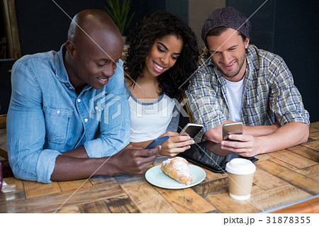 Smiling friends using smart phones at table in coffee shop 31878355