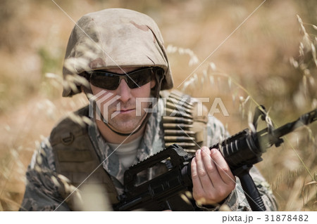 Military soldier hiding in grass while guarding with a rifle Military soldier hiding in grass while guarding with a rifle 31878482