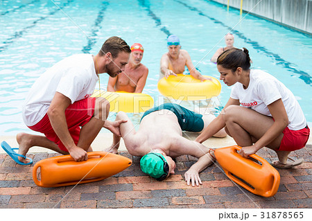 Male and female lifeguards helping unconscious man 31878565